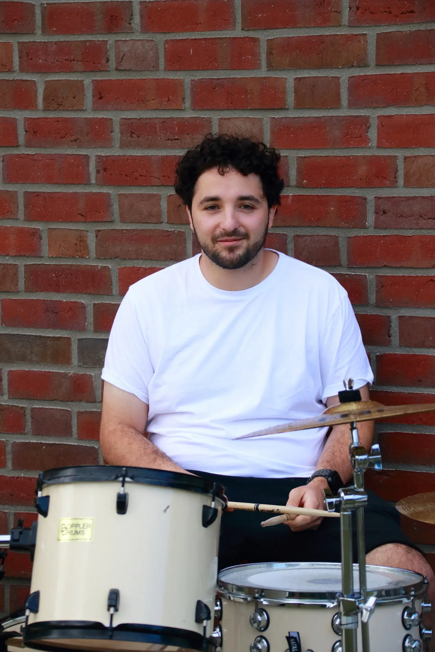 Schlagzeuger mit Drumsticks hinter seinem weißen Schlagzeug