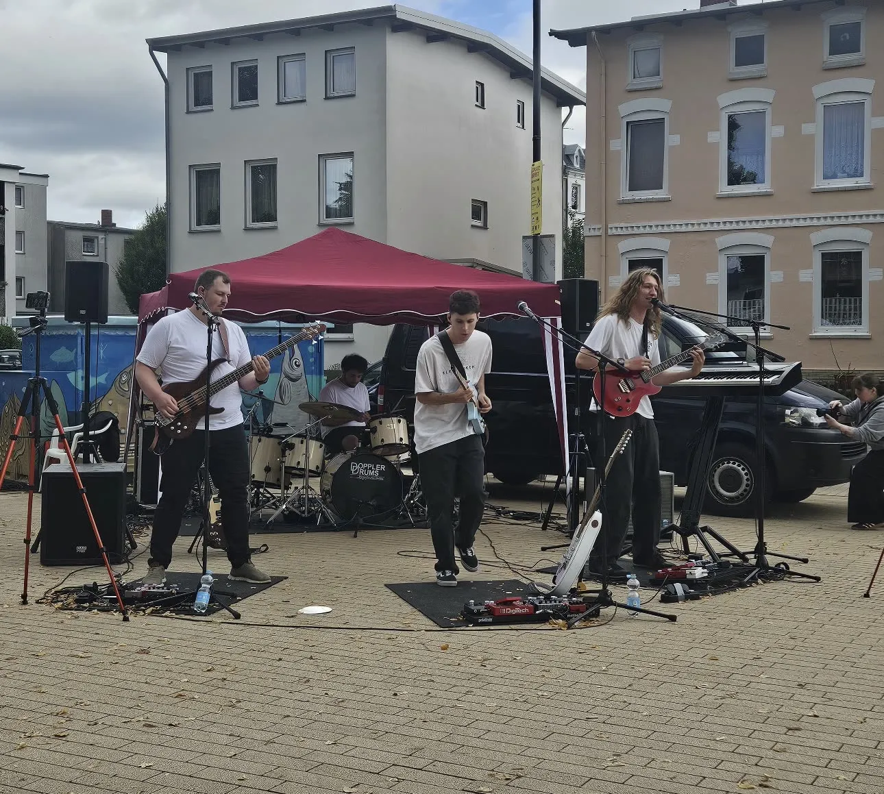 Die Baltigos spielen gemeinsam mit Gitarren, Bass und Schlagzeug auf einer Open-Air-Bühne